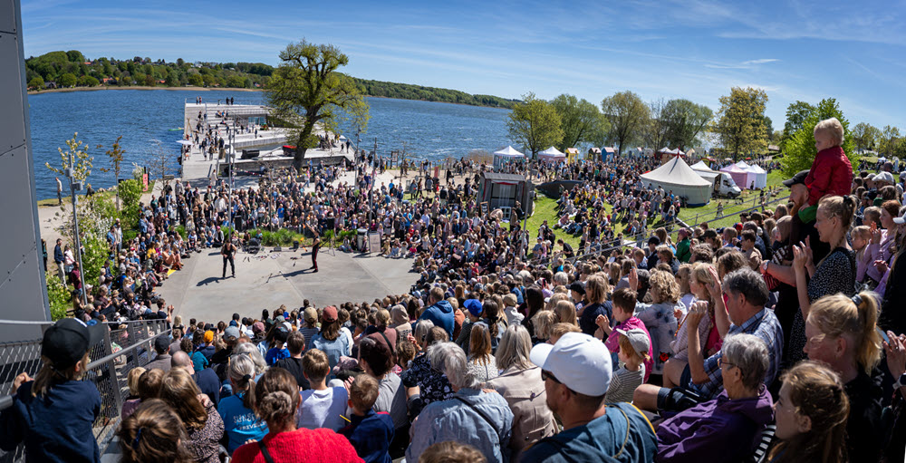 En megetg stor folkemængde ser et show ved Bybadet i Skanderborg med blå himmel.